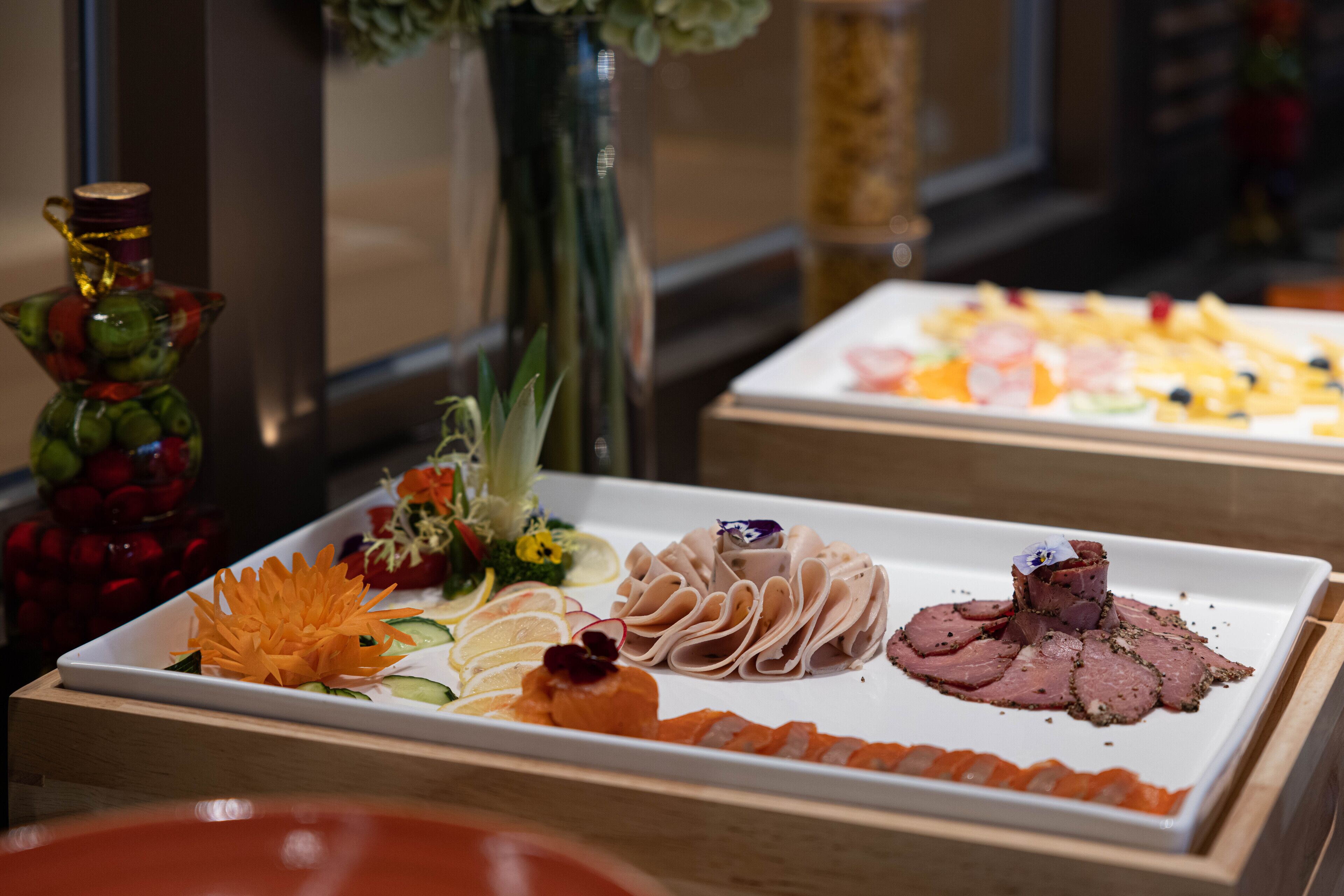 Ein Buffet mit verschiedenen Speisen, darunter Aufschnitt, Käse und Obst.