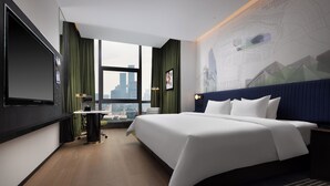 A modern hotel room with a large bed, a flat-screen TV, a desk with a chair, and a view of the cityscape through a large window. - Hampton by Hilton Shenzhen Science Park (Shenzhen)