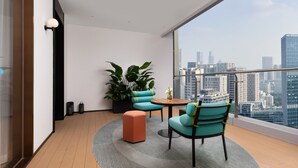 A modern balcony with a city view, featuring a seating area with a table, a potted plant, and a small rug. - Hampton by Hilton Shenzhen Science Park (Shenzhen)