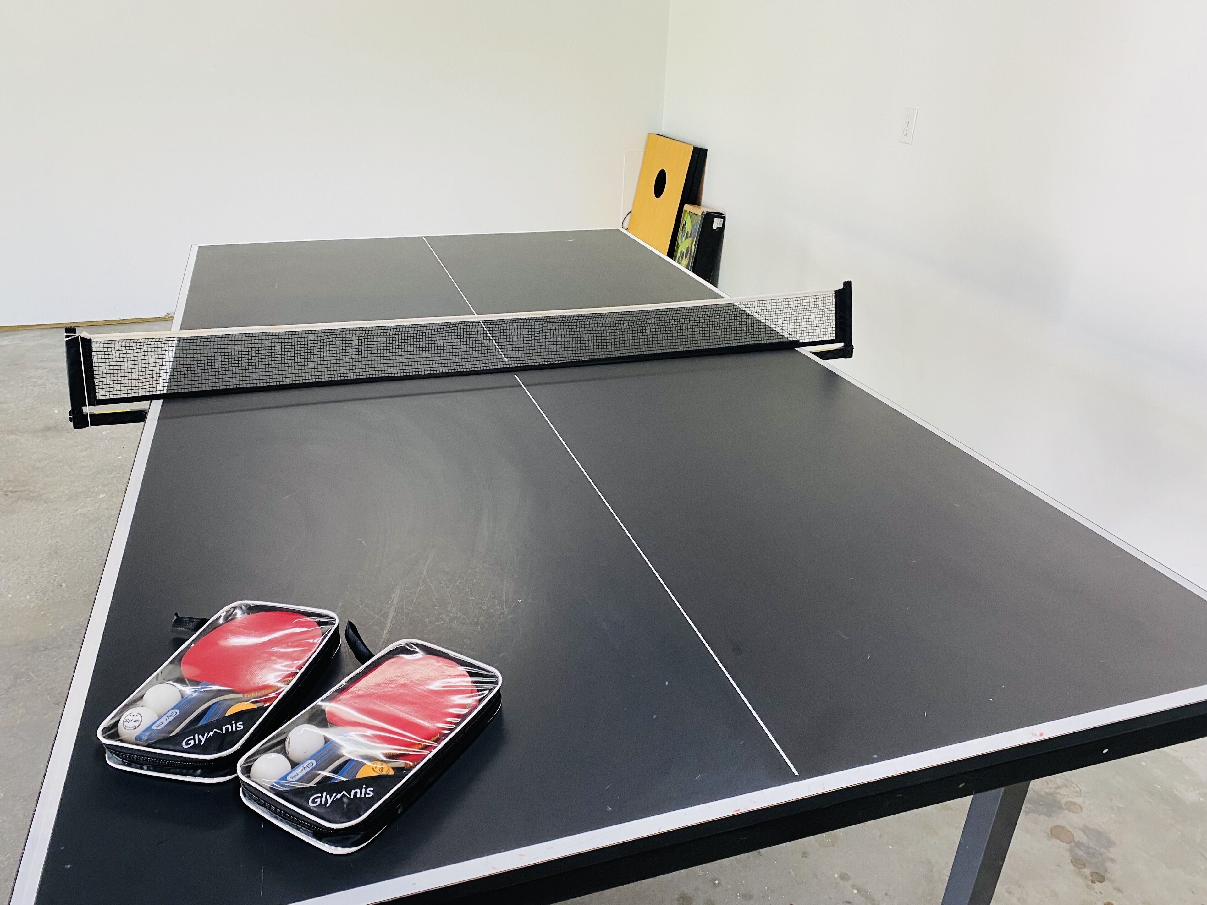 A ping pong table with two ping pong paddles and balls in a case.