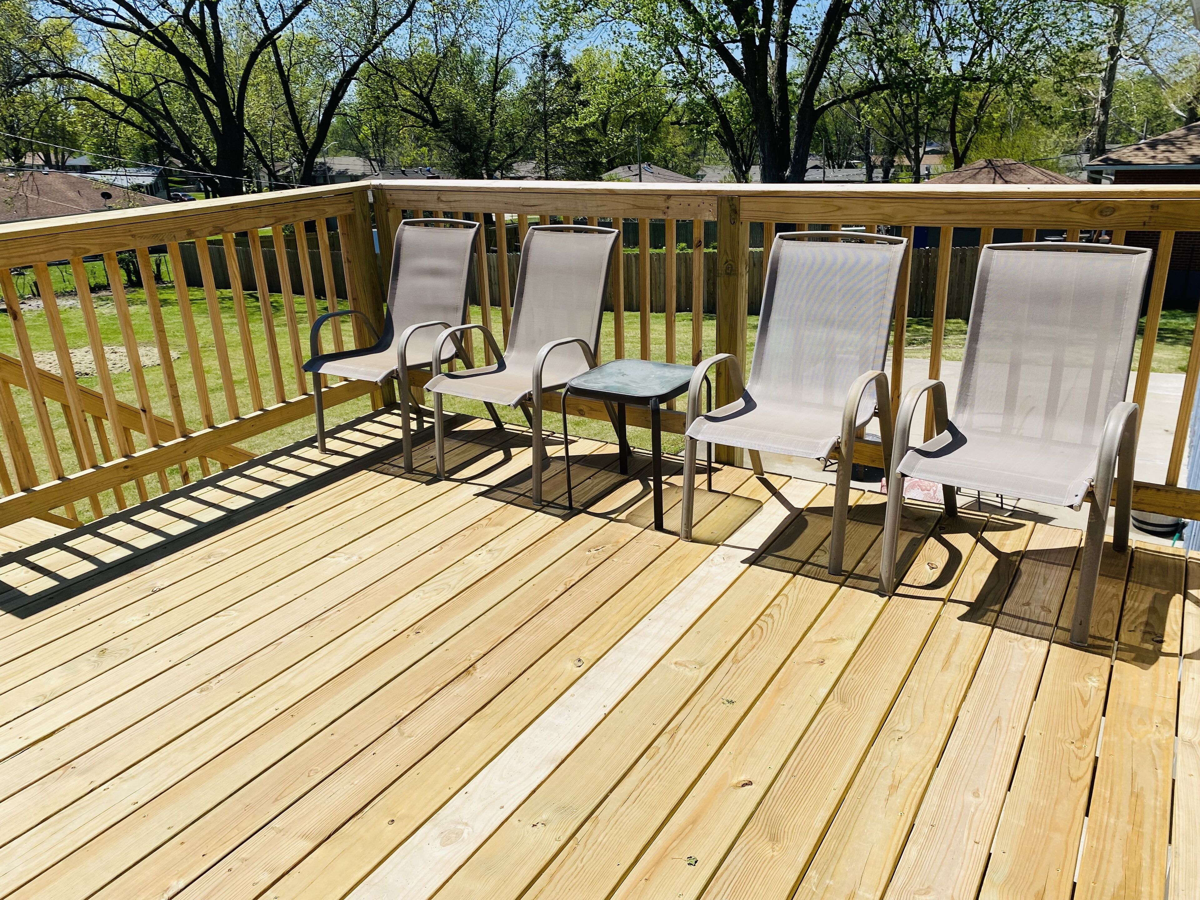 Une terrasse en bois avec quatre chaises et une table.