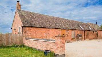 Un bâtiment en briques avec un toit en pente, une clôture en bois et une allée gravillonnée.