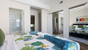 A modern hotel room with a large bed, a shower area, and a separate bathroom.