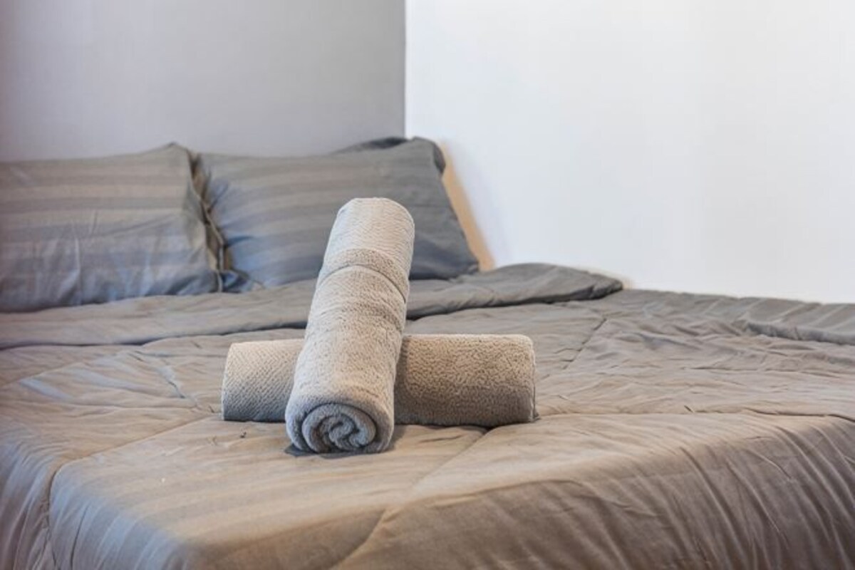 A bed with a rolled-up blanket and pillows.