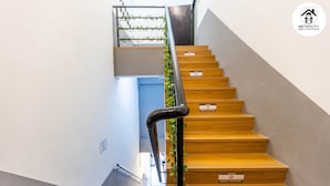 A modern staircase with wooden steps and a metal handrail, leading to an upper floor. - MetroCity Backpackers (Kuching)
