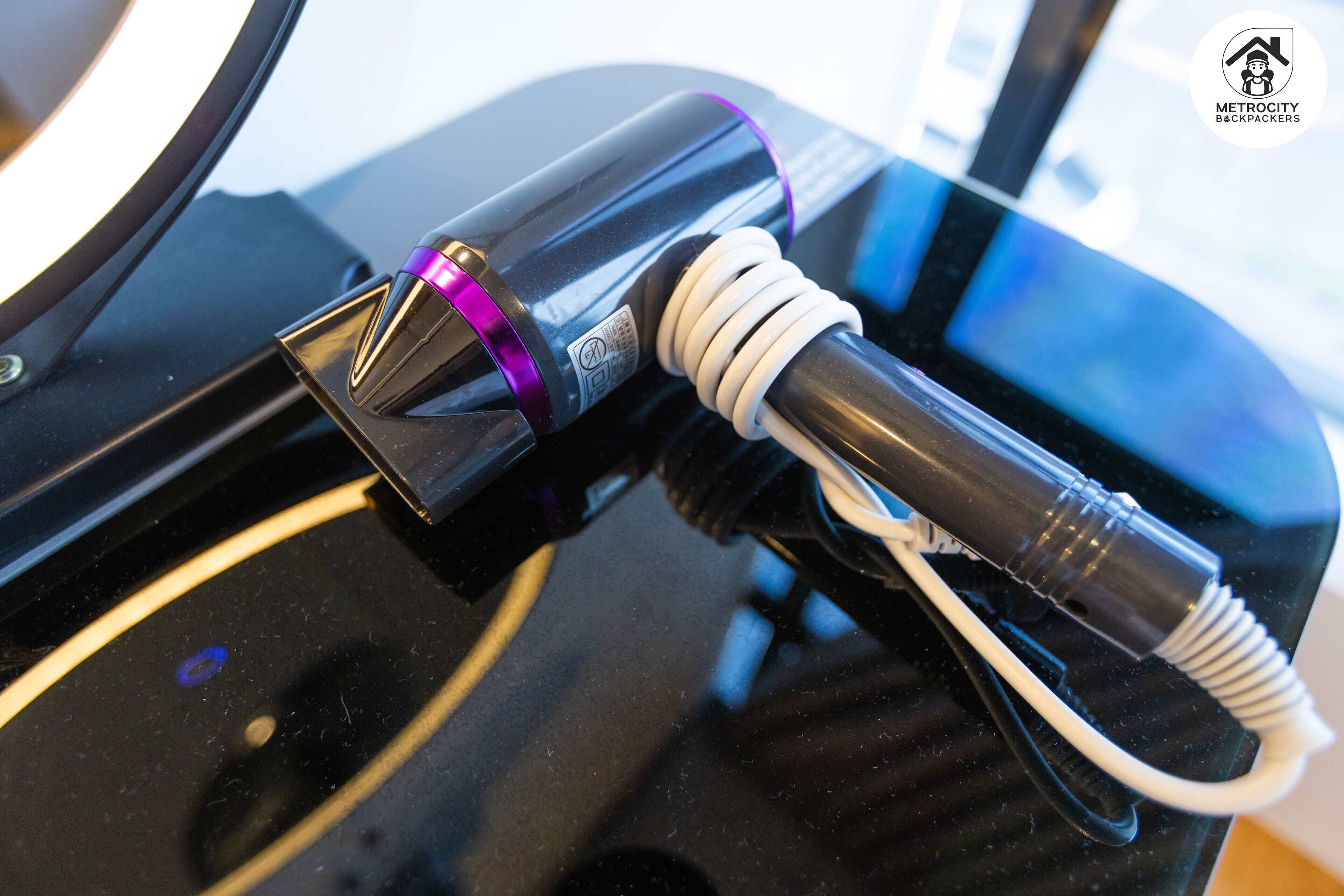 A charging station with a purple light indicator and a white cable connected to a device.
