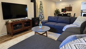 Un soggiorno con una grande televisione a schermo piatto, un camino, un albero di Natale, un divano e un tavolino da caffè.