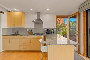 A modern kitchen with wooden cabinets, a gas stove, and a view of red rock formations. - Eagle Dancer Spa Sanctuary | Picture Perfect Views (Sedona)
