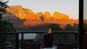 Une terrasse dotée de deux chaises longues et d’un foyer extérieur, offrant une vue sur un canyon aux formations rocheuses spectaculaires.