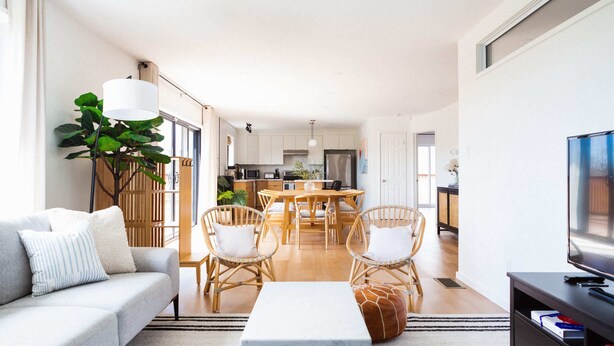 Uma sala de estar moderna com sofá, mesa de centro e área de jantar com cadeiras.