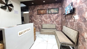 Un área de recepción con pared de mármol, mostrador de recepción y zona de estar.
