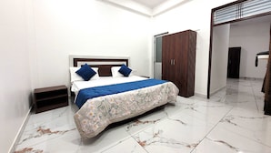 Una habitación con cama, armario y baño visible a través de una puerta abierta.