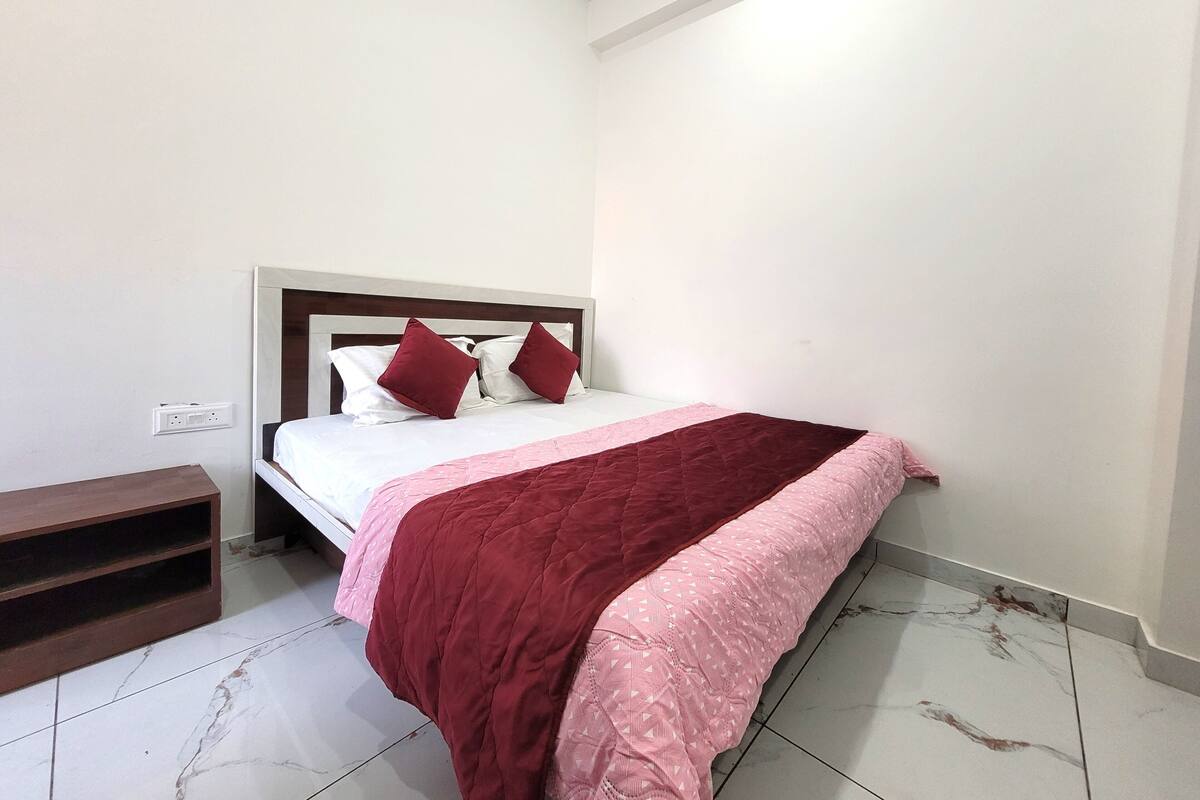 A bedroom with a bed, a nightstand, and a wall socket.