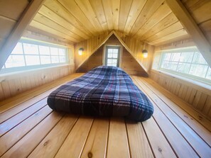 A high-ceilinged attic bedroom with wooden floors and two windows. - Lakeside Tiny Cozy Retreat (Ulster)