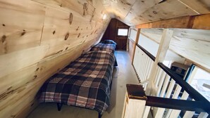 A narrow attic bedroom with two beds, wooden walls, a small window, and a wooden staircase. - Willow Point Cabin:Brenchly Lake (Ulster)