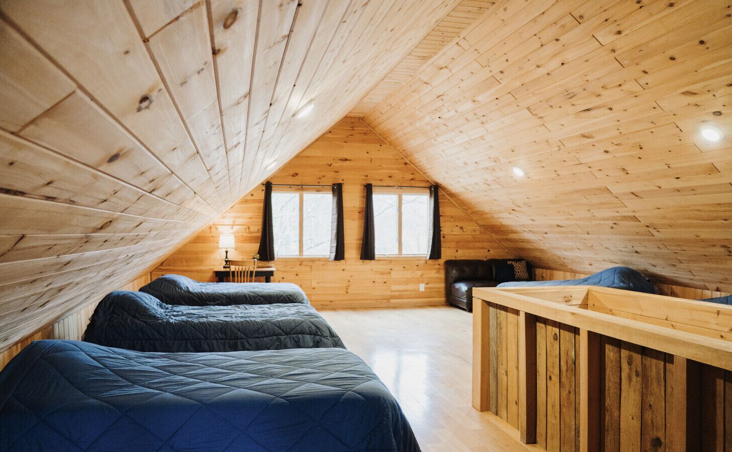 Une chambre confortable située dans les combles, avec des murs en bois, un plafond en pente et deux lits.