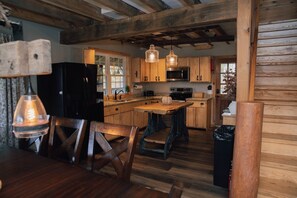 Una cocina rústica con armarios de madera, una isla central e iluminación colgante.