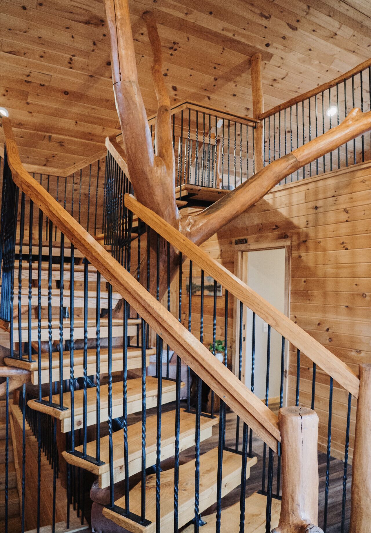 Una escalera de madera con diseño en espiral, baranda de madera y una puerta al final.