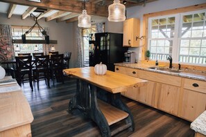 Una cocina rústica con una mesa de madera, un ventanal grande y una chimenea de piedra.