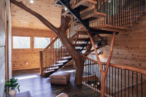 Un interior de madera con una escalera espiral, un banco y una planta en maceta.