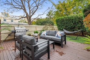 An outdoor deck with a grill, a sofa set, and a hammock.