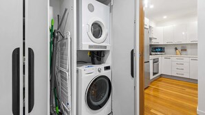 Uma lavanderia compacta com máquina de lavar, secadora e aspirador de pó.