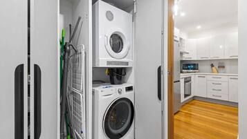 A compact laundry room with a washing machine, dryer, and a vacuum cleaner.
