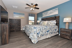A bedroom with a bed, a ceiling fan, a nightstand, a dresser, and artwork on the walls. - Fs3993ha - 6 Bedroom Villa In Champions Gate Resort, Sleeps Up To 12, Just 9 Miles To Disney (Davenport)