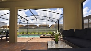 An outdoor patio area with a pool, a seating area with a sofa and table, and a view of neighboring houses. - Fs4078ha - 7 Bedroom Villa In Windsor At Westside Resort, Sleeps Up To 14, Just 7 Miles To Disney (Kissimmee)