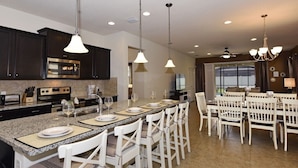 A modern kitchen with dark cabinets, granite countertops, and pendant lighting. - Fs4078ha - 7 Bedroom Villa In Windsor At Westside Resort, Sleeps Up To 14, Just 7 Miles To Disney (Kissimmee)