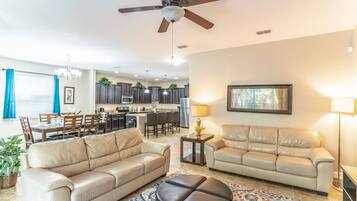 A living room with two beige sofas, a coffee table, and a ceiling fan.