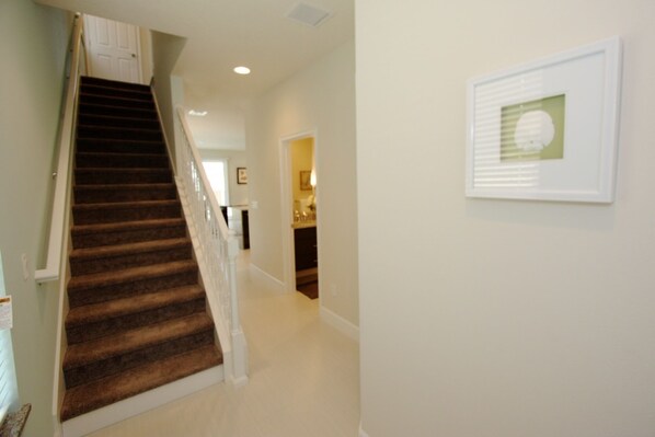 A carpeted staircase leading to a landing with a framed picture on the wall.