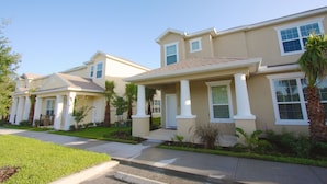 A row of modern, two-story houses with beige exteriors and white trim. Each house features a front porch with columns and a covered entryway. - It2561 - 3 Townhome in Serenity, Sleeps Up To 7, Just 5 Miles To Disney (Clermont)