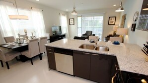 A modern kitchen with a large island, built-in dishwasher, and a dining area with a table and chairs. - It2561 - 3 Townhome in Serenity, Sleeps Up To 7, Just 5 Miles To Disney (Clermont)