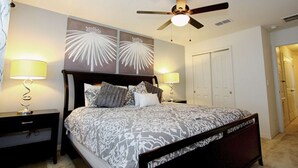 A bedroom with a bed, two bedside tables, a ceiling fan, and a door.