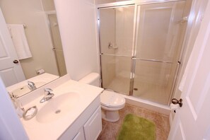 Une salle de bain équipée d’une douche, de toilettes, d’un lavabo et d’un miroir.