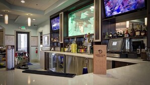 A bar area with a counter, bar stools, a television screen, and a variety of bottles and glasses. - Grh9372ha - Champions Gate Resort - 5 Bed 4 Baths Villa (Davenport)