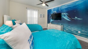 A bedroom with two beds, a ceiling fan, a TV, and an ocean-themed mural. - Grh9381ha - Champions Gate Resort - 4 Bed 3 Baths Townhome (Davenport)
