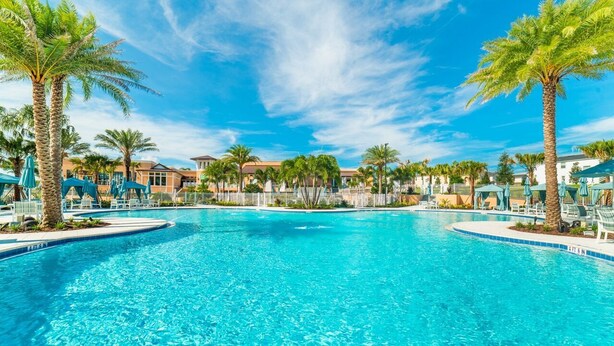 A large outdoor swimming pool surrounded by palm trees and lounge chairs, with a clear blue sky above. - Grh9389ha - Solara Resort - 4 Bed 3 Baths Villa (Kissimmee)