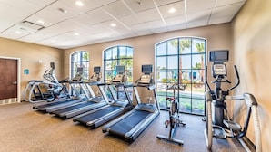 A fitness center with treadmills, elliptical machines, and a large window providing a view of the outdoors. - Grh9419ha - Windsor At Westside Resort - 6 Bed 4 Baths Villa (Kissimmee)