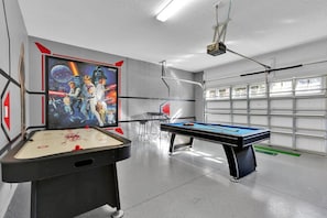 A pool table with a Star Wars-themed mural, a projector, and a garage door in the background. - Grh9420ha - Windsor At Westside Resort - 6 Bed 4.5 Baths Villa (Kissimmee)