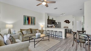 A modern living room with a sofa, coffee table, and a kitchen area with bar stools.