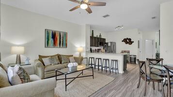 A modern living room with a sofa, coffee table, and a kitchen area with bar stools.