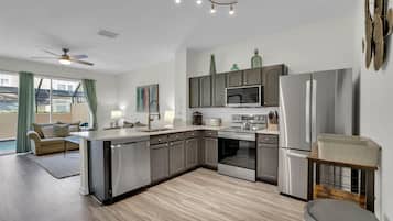 A modern kitchen with grey cabinets, stainless steel appliances, and a central island.