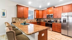 A modern kitchen with wooden cabinets, granite countertops, and stainless steel appliances. - Fs9492ha - Champions Gate Resort - 6 Bed 6 Baths Villa (Davenport)