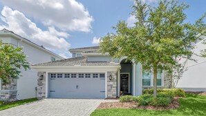A modern two-story house with a stone facade, a tiled roof, and a well-maintained lawn. - Fs9493ha - Champions Gate Resort - 6 Bed 6 Baths Villa (Davenport)