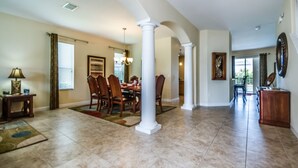 A spacious dining area with a high ceiling, white columns, and a large dining table with chairs. - Fs9534ha - The Shire at West Haven - 5 Bed 4 Baths Villa (Davenport)