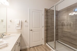 A modern bathroom with a glass shower enclosure, a white vanity with a sink, and a door leading to another room. - Fs9584ha - Sonoma Resort - 10 Bed 8 Baths Villa (Kissimmee)