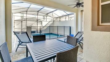 A covered patio with a pool, outdoor seating, and a ceiling fan.