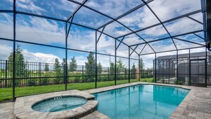 A swimming pool with a hot tub, surrounded by a covered patio with a view of a grassy area and trees. - Fs9601ha - Solara Resort - 9 Bed 6 Baths Villa (Kissimmee)